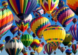 Cluster of colorful hot air balloons in sky.