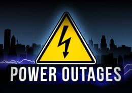 Warning sign for power outage against a dark city skyline.