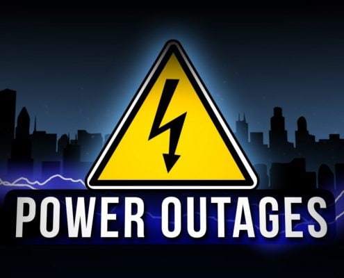 Warning sign for power outage against a dark city skyline.
