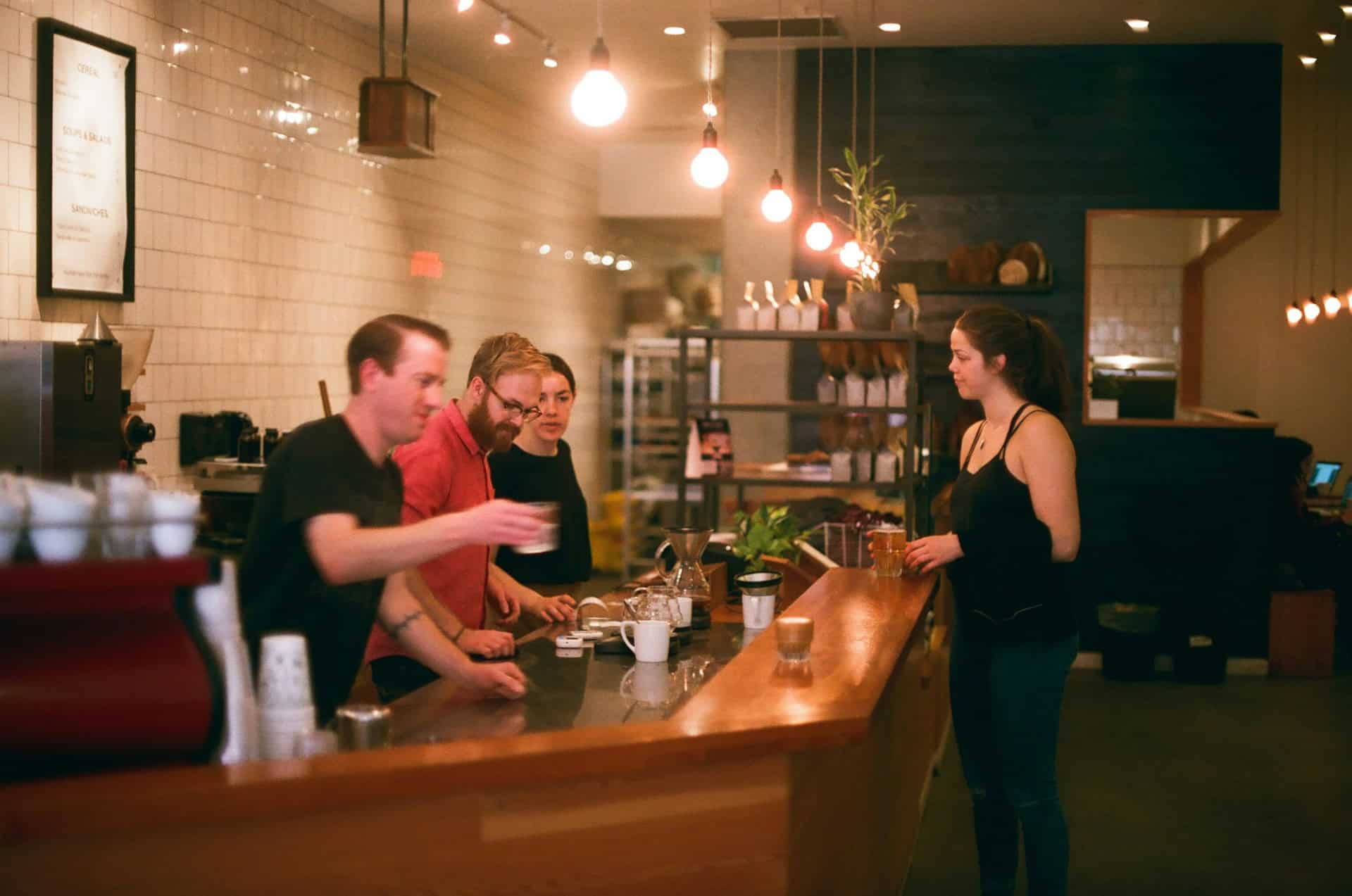 A customer speaking with two pharmacists at the counter inside a well-lit pharmacy.